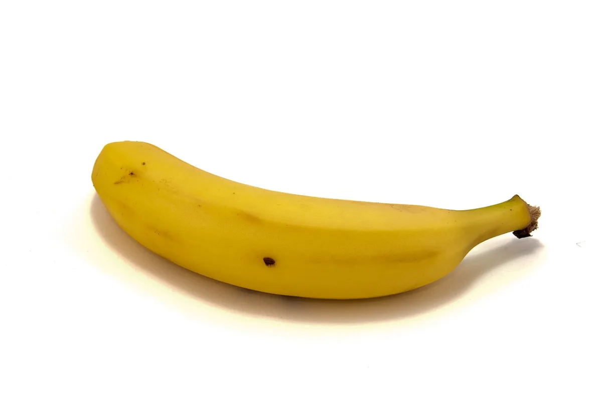 Een enkele gele banaan tegen een witte achtergrond.