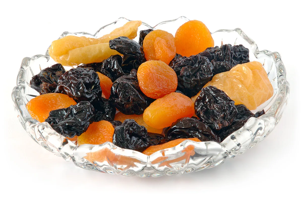 Glazen schaal met gedroogd fruit: pruimen, abrikozen en gedroogde peer.
